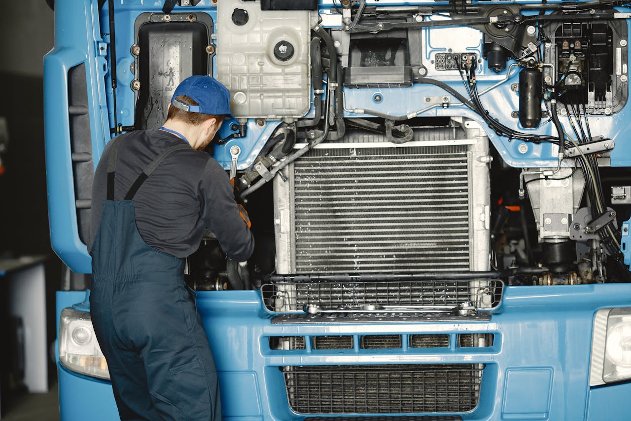 about-us Mechanic in uniform working on a truck engine in an industrial workshop. Perfect for automotive maintenance themes.