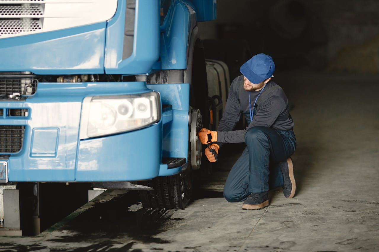 services-04 Mechanic in a garage fixing the wheel of a blue truck. Industrial vehicle maintenance.