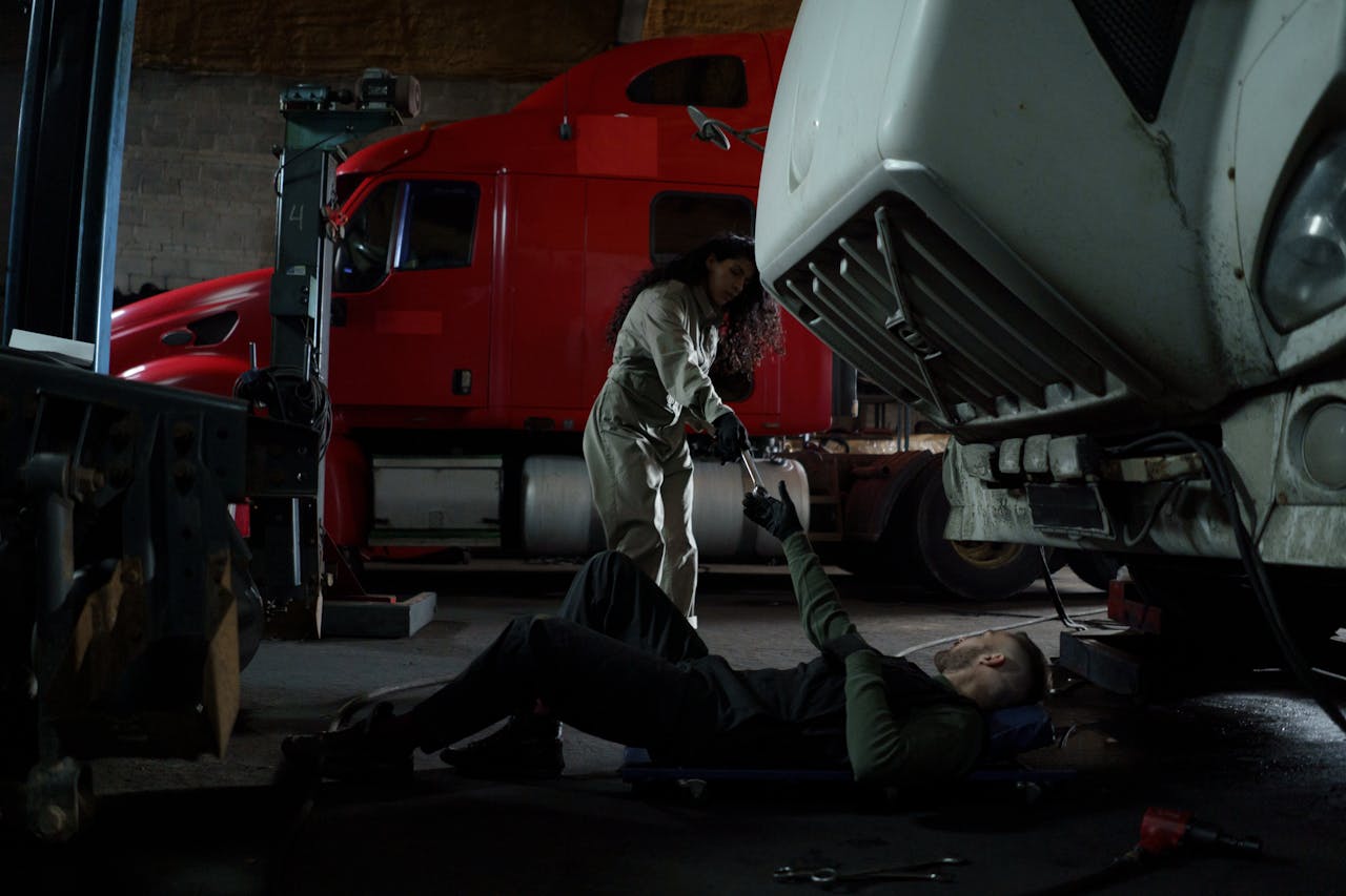 services-02 Two mechanics working together to repair a truck in a dimly lit garage setting.